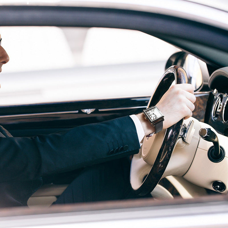 Person driving a car with a close-up of their hand on the steering wheel.