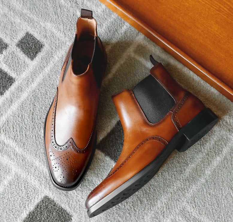 Pair of brown leather boots on a textured surface with a wooden object in the background.