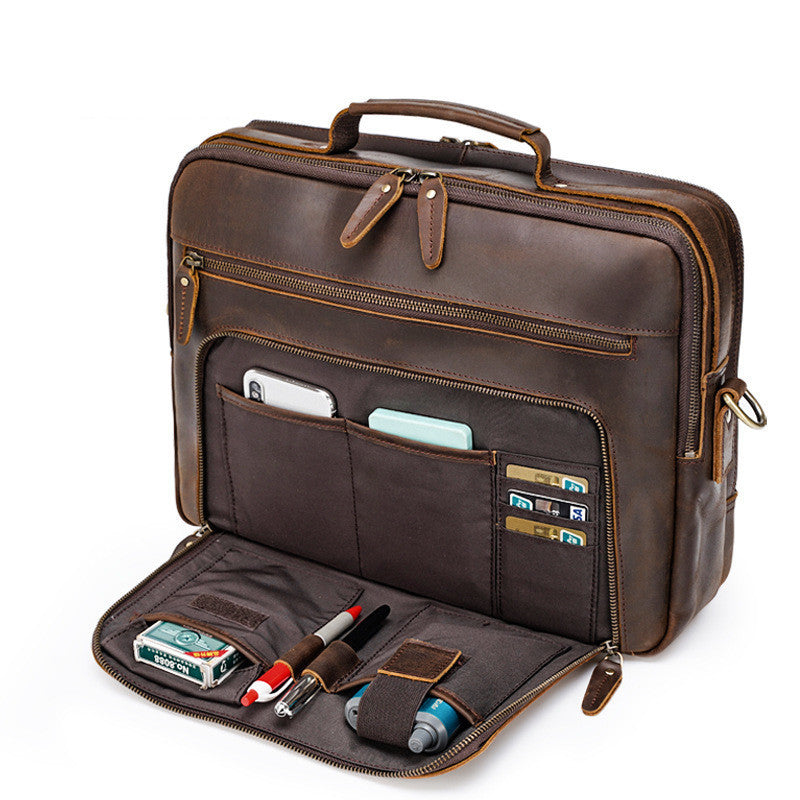 Brown leather briefcase with compartments and items on a white background