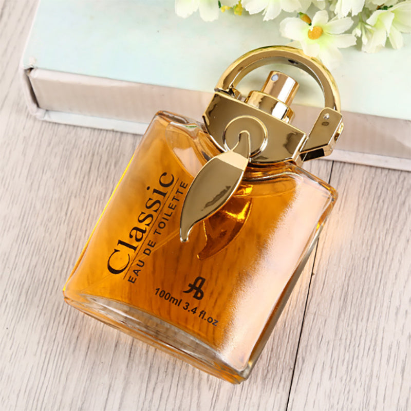 Perfume bottle labeled 'Classic' on a wooden surface with flowers in the background