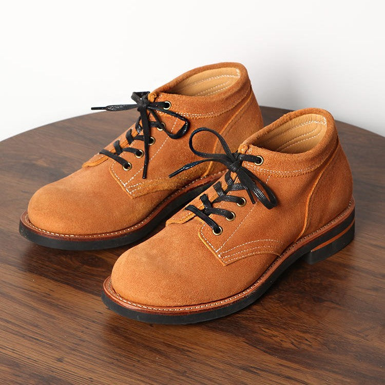 Pair of brown leather shoes with black laces on a wooden surface