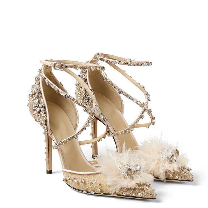 Beige high-heeled sandals with embellishments and feathers on a white background