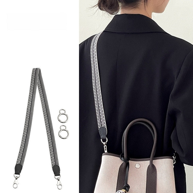 Person wearing a black coat with a beige handbag, featuring a strap with metal rings.