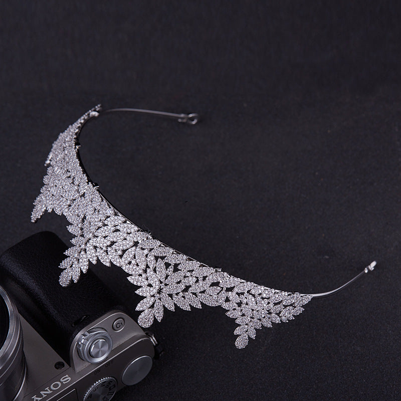 Silver leaf-shaped headband on a black background with a Sony camera.