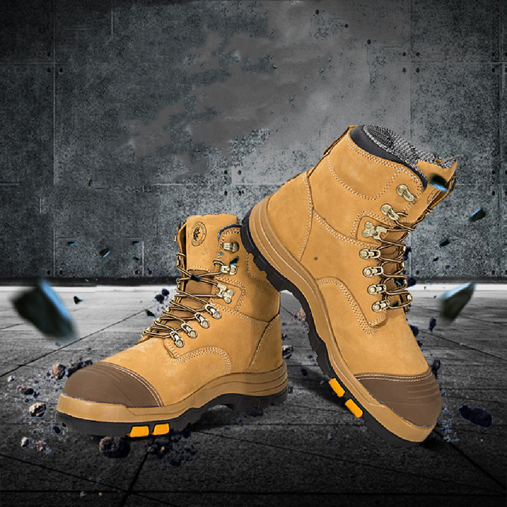 Pair of tan work boots with orange accents on a dark concrete floor.