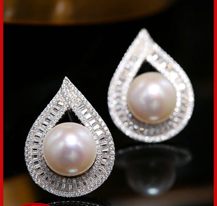 Teardrop-shaped pearl earrings with diamond accents on a dark background
