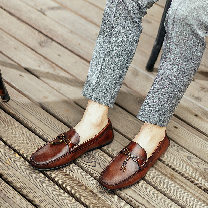 Brown loafers worn with gray pants on a wooden floor