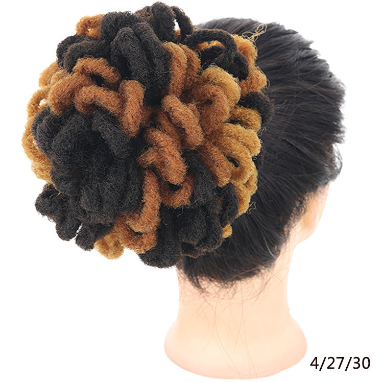 Mannequin head with a bun made of black, brown, and beige hair extensions on a white background.