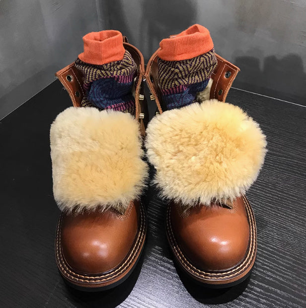 Brown boots with fluffy pom-poms and patterned socks on a dark surface
