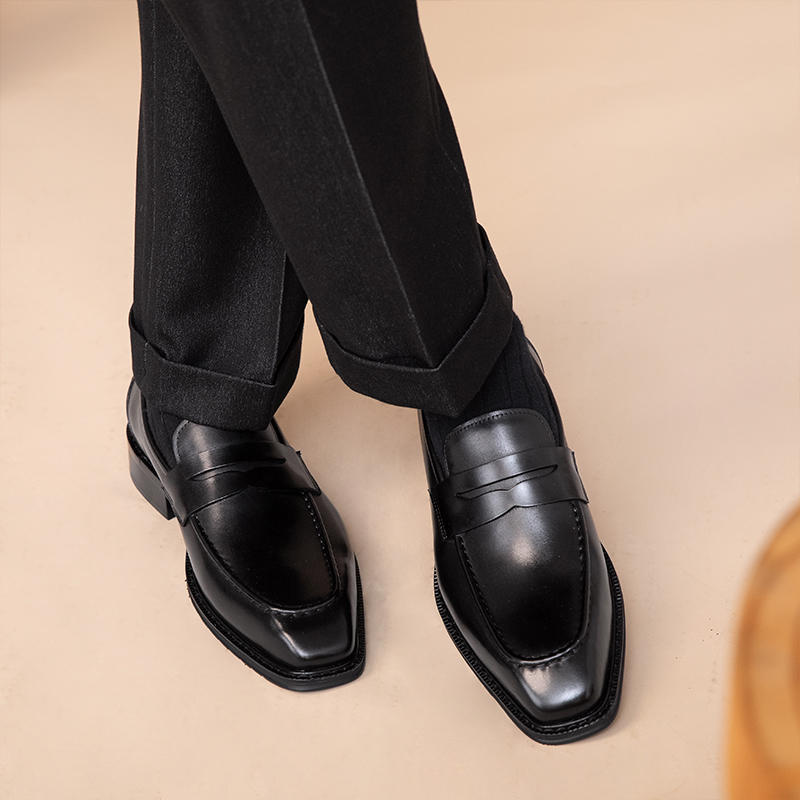 Black dress shoes worn with black pants on a beige background