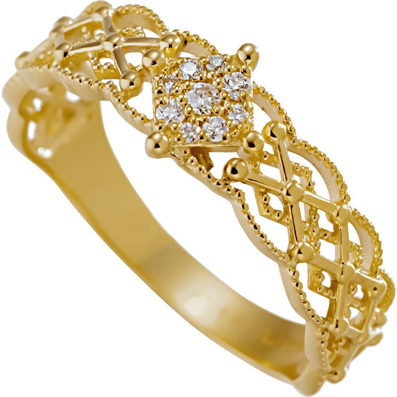 Gold ring with intricate design and small diamonds on a white background