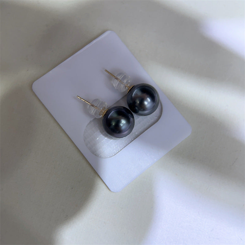 Pair of black pearl earrings on a white card with a neutral background