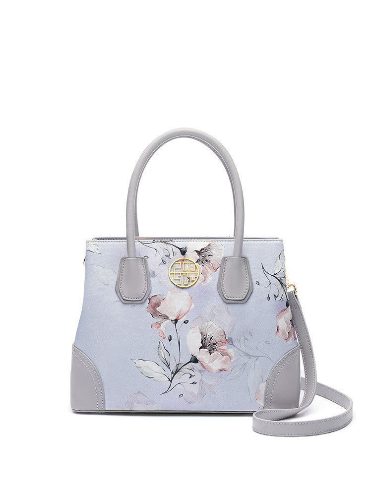 Floral handbag with gray handles and strap on a white background