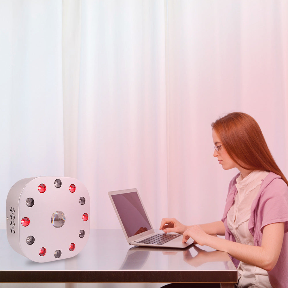Woman using a laptop at a table with a unique clock on the side, against a light curtain background.