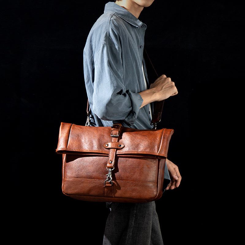 Person holding a brown leather bag against a black background