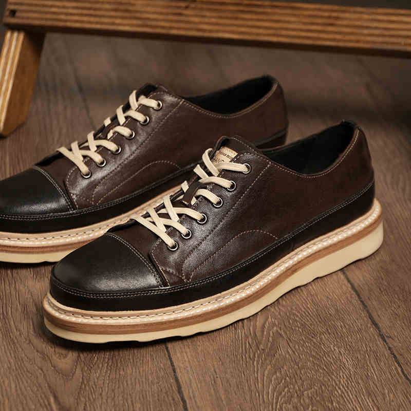 Pair of brown leather shoes with white laces on a wooden surface