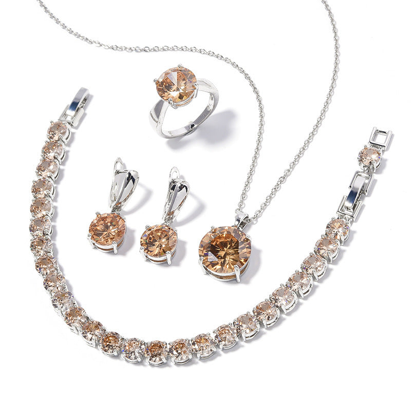 Jewelry set with necklace, bracelet, ring, and earrings featuring brown gemstones on a white background.