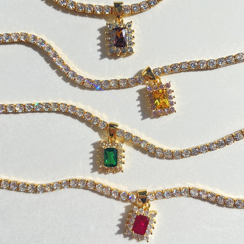 Gold necklaces with gemstone pendants on a light gray background