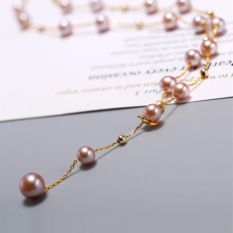Pearl necklace with gold chain on a light gray surface