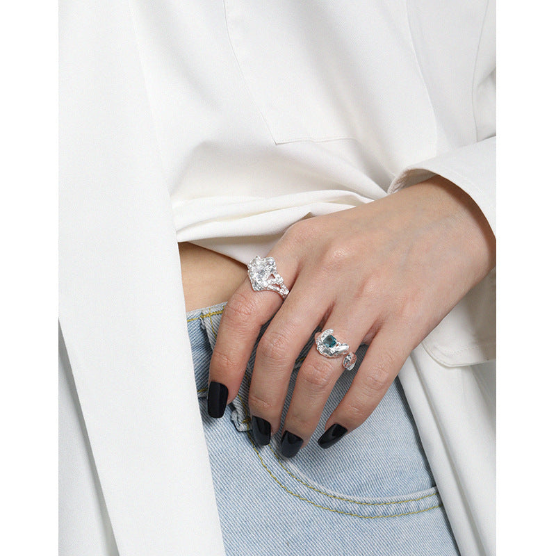 Close-up of a hand wearing two rings with a white coat and denim jeans in the background