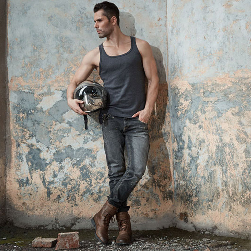 Man holding a helmet against a textured wall