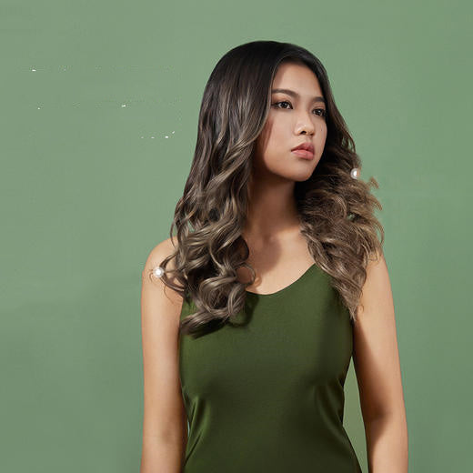Woman with long, wavy hair wearing a green dress against a green background