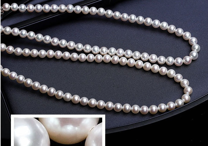 Pearl necklace on a dark surface with close-up inset showing pearls.