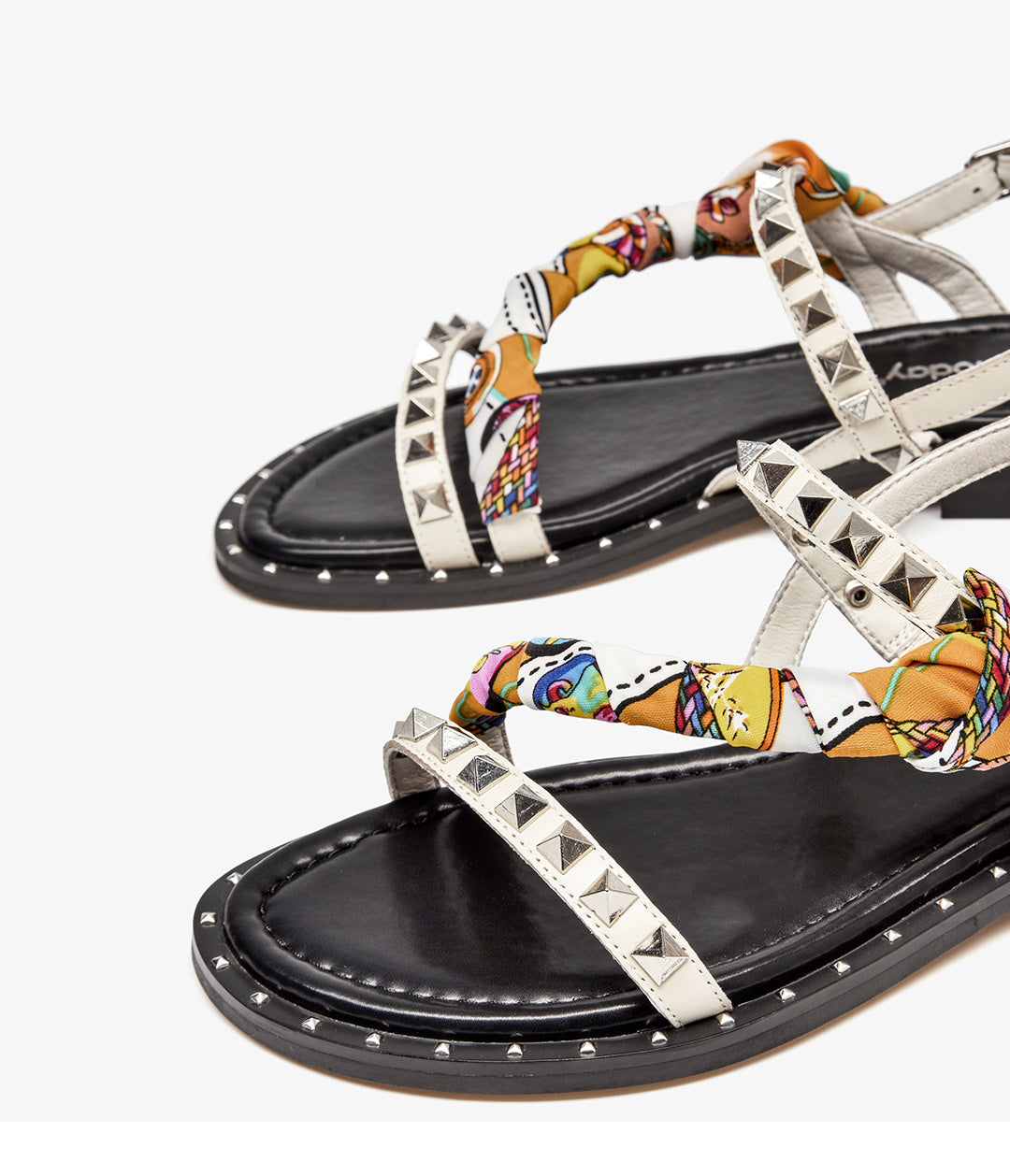 Pair of sandals with colorful strap design and studded details on a white background
