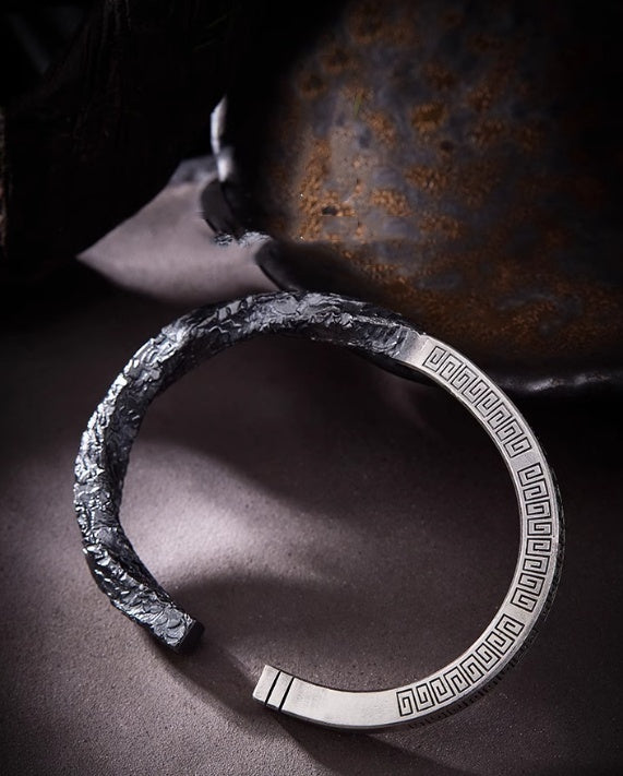 Silver bracelet with textured design on a dark background