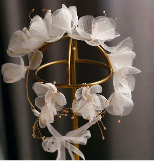 White floral headpiece on a stand against a dark background