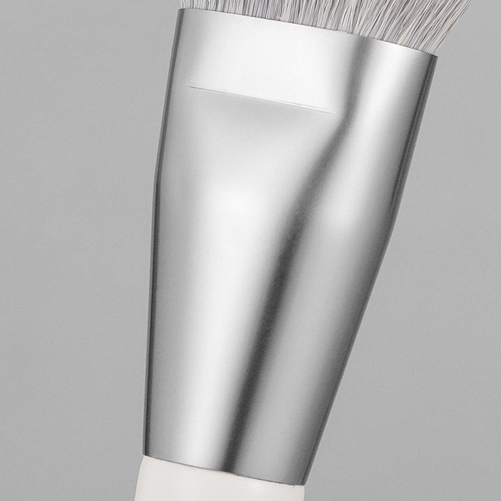 Close-up of a silver makeup brush with a gray background
