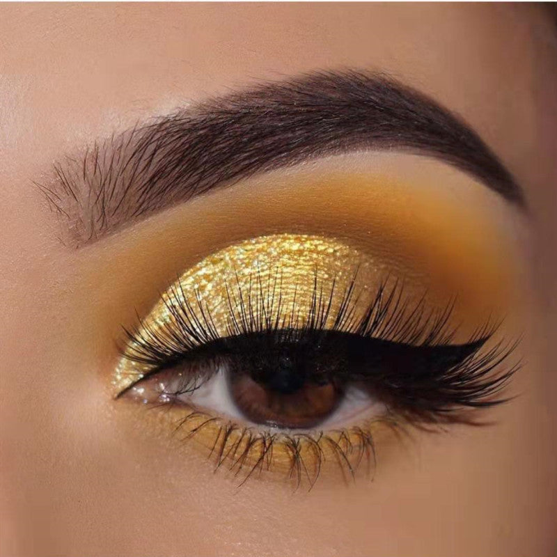 Close-up of an eye with gold makeup and long lashes