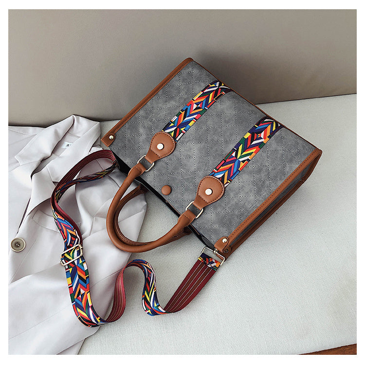 Gray bag with a colorful strap on a white surface