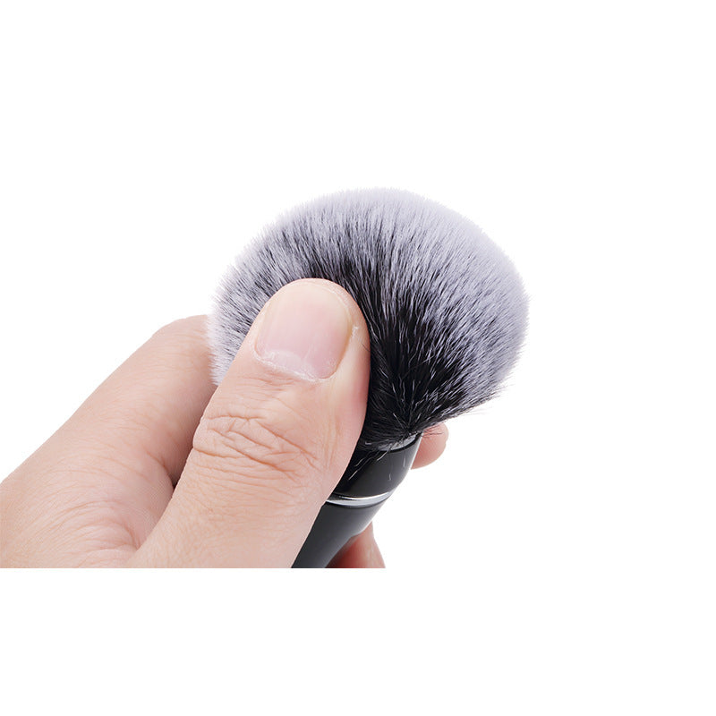 Makeup brush held by a hand on a white background