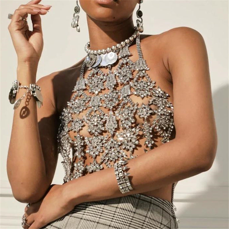 Person wearing a sparkling silver top with intricate designs, surrounded by jewelry.