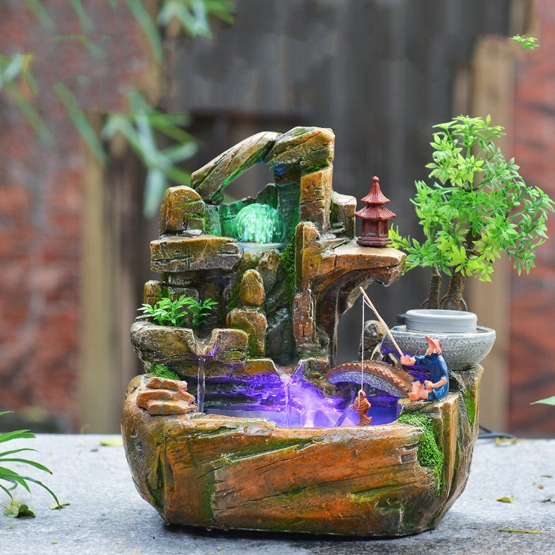 Decorative garden water fountain with rocks, plants, and a small pagoda-like structure.
