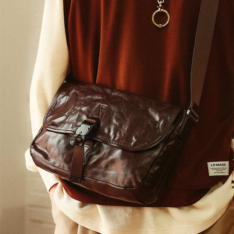 Brown leather bag worn over shoulder with a neutral background