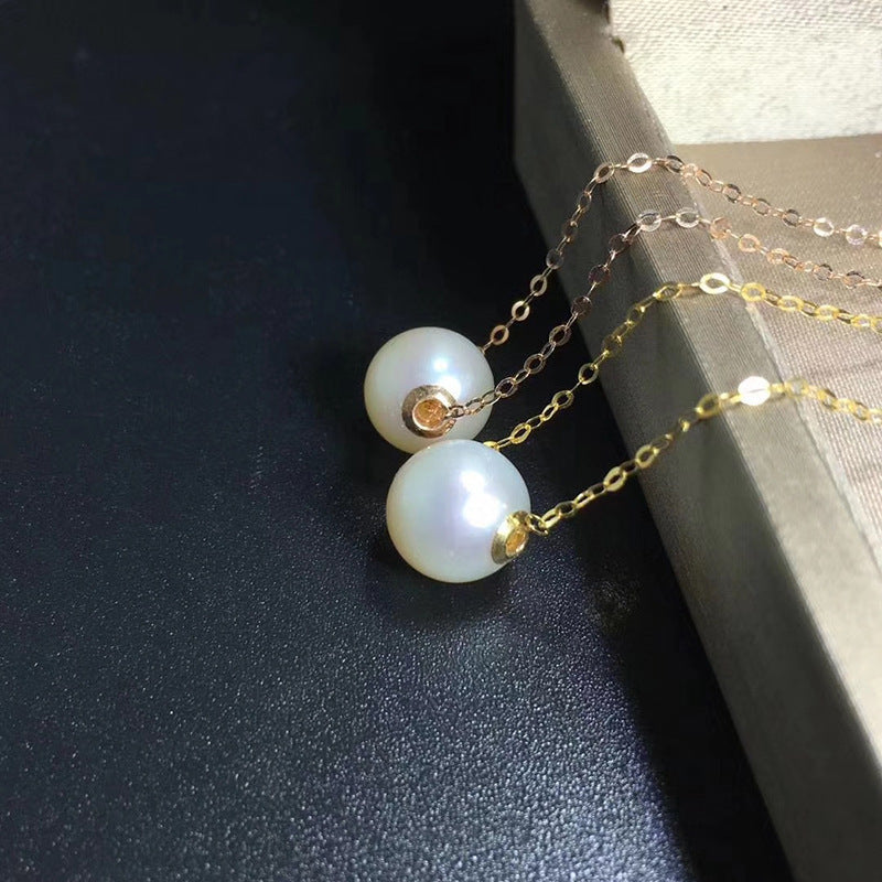 Pearl necklace with gold chain on a dark surface