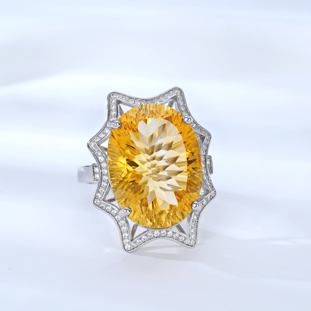 Ring with a large yellow gemstone and diamond-studded band on a light gray background