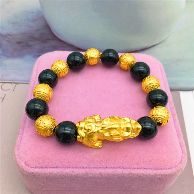 Bracelet with black beads and gold accents on a pink cushion