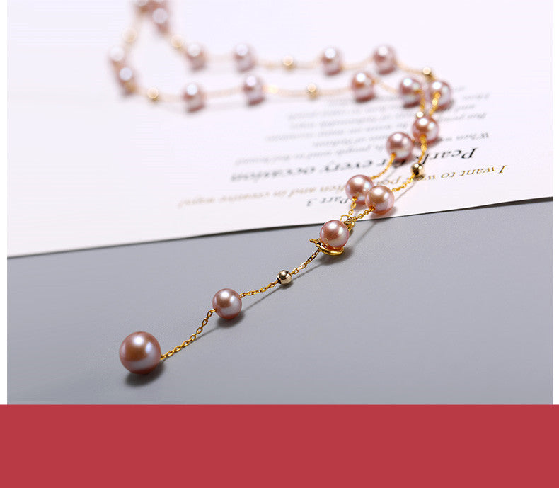 Pearl necklace with gold chain on a gray surface