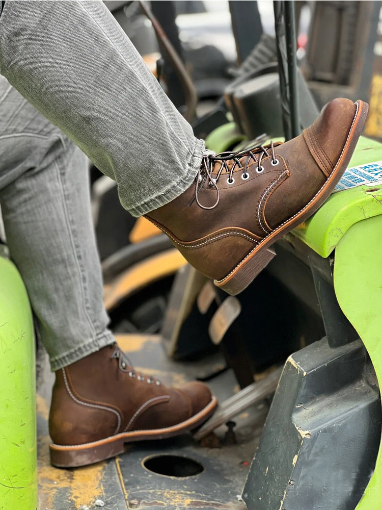 Brown leather boots worn with gray jeans on a mechanical surface