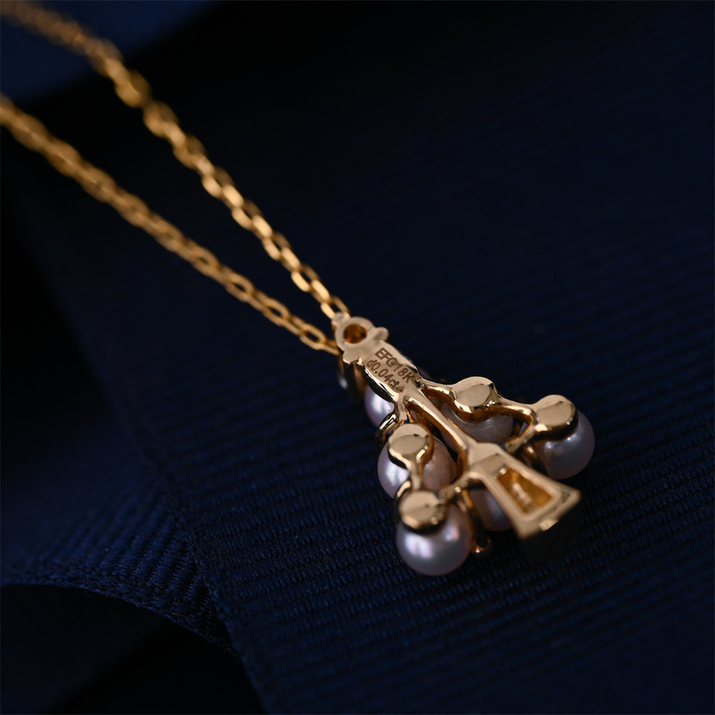 Gold necklace with a pendant featuring pearls on a dark fabric background