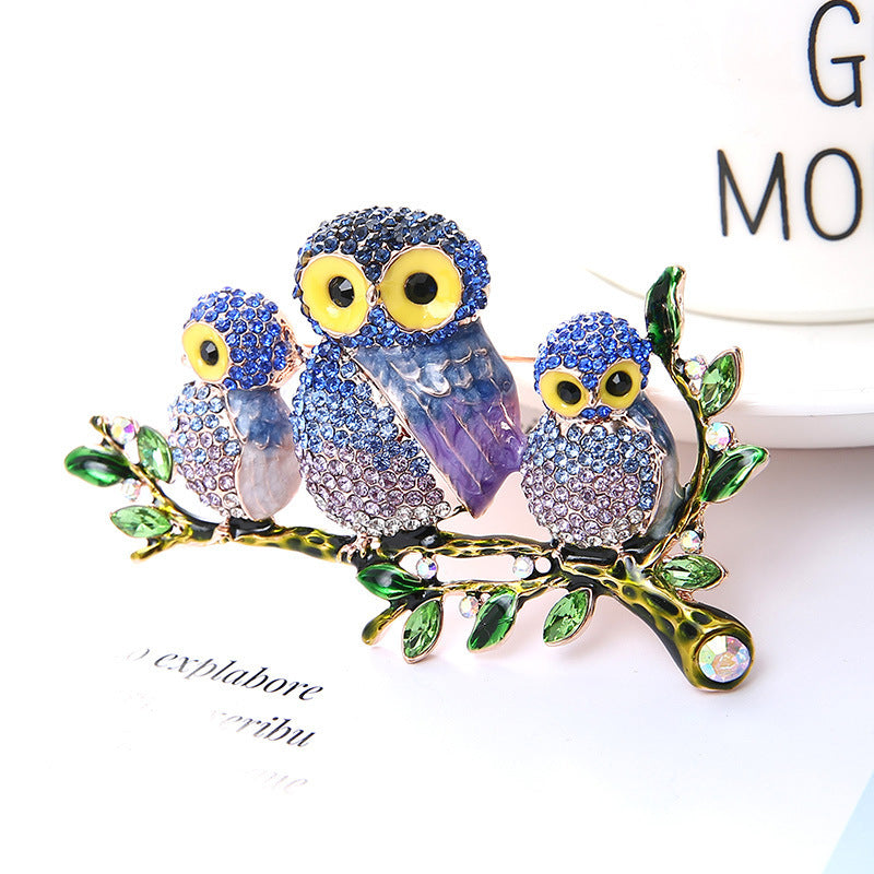 Decorative brooch with three owl designs on a branch