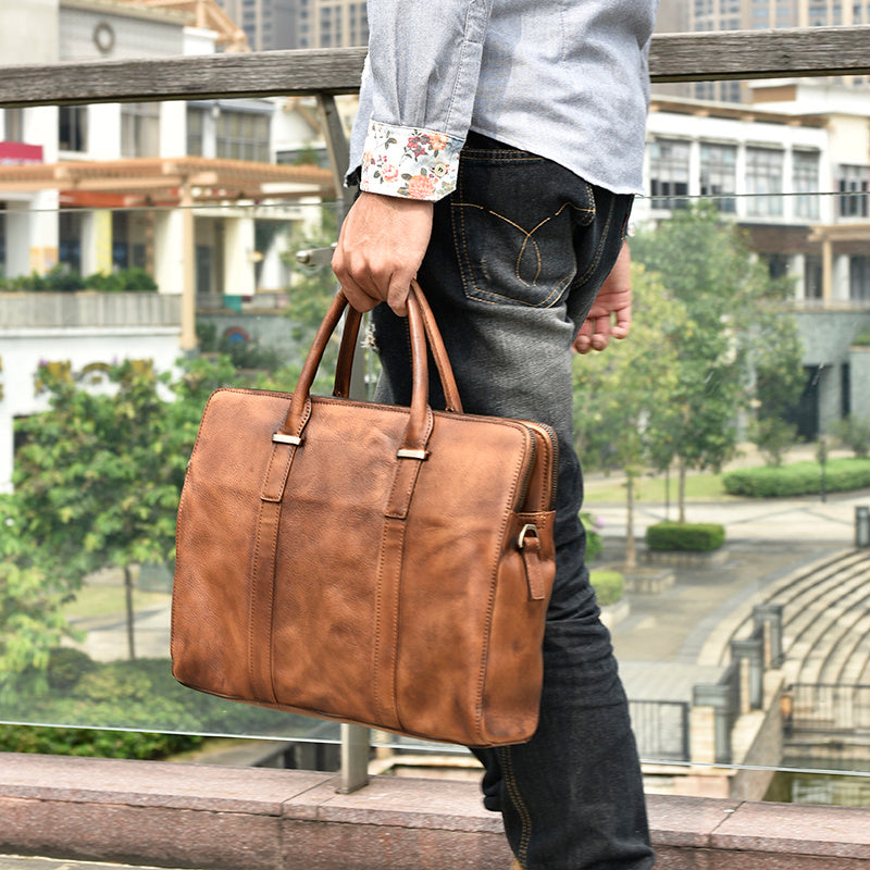 Person holding a brown leather briefcase in an urban setting