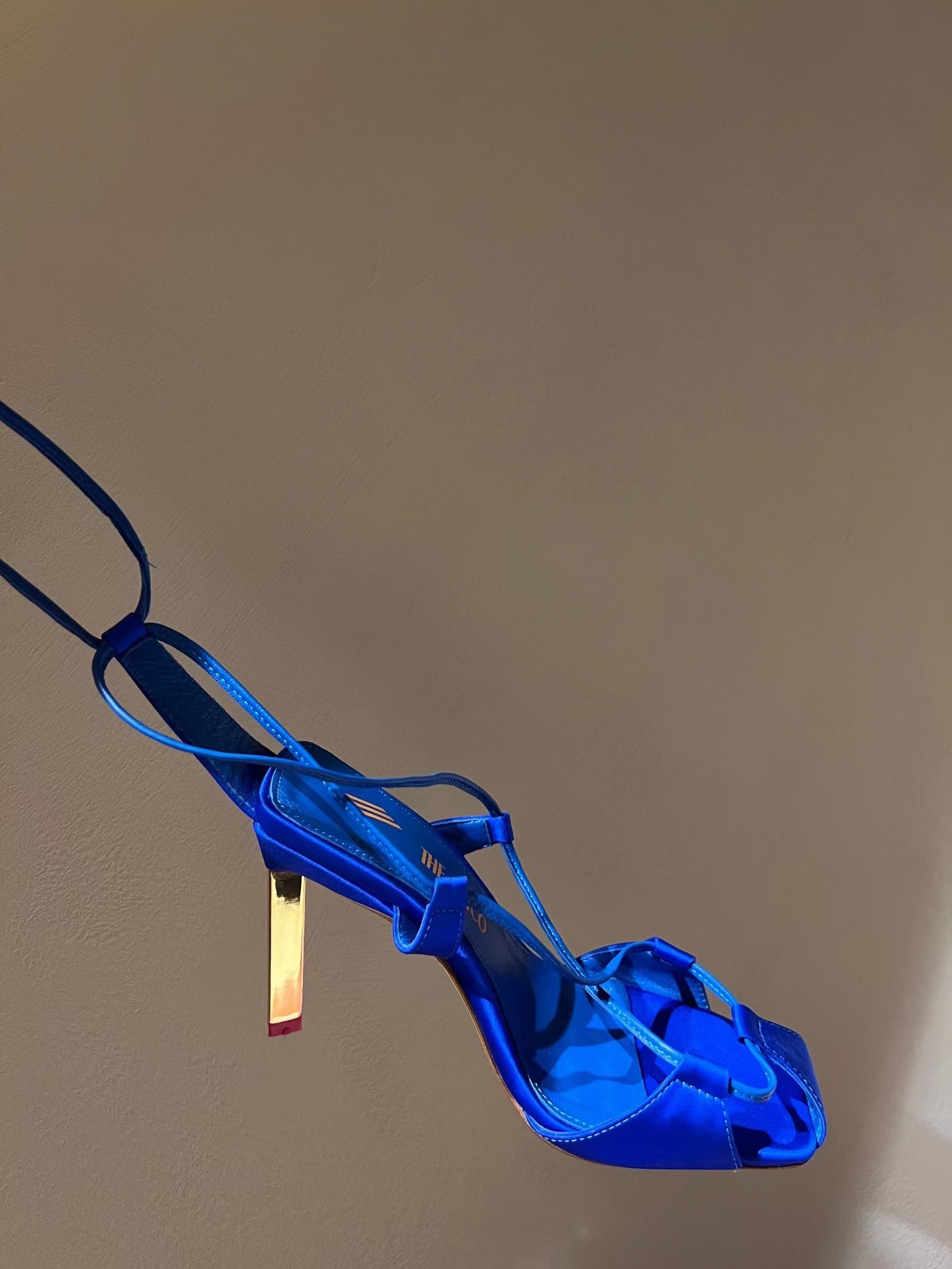 Blue high-heeled shoe on a beige background