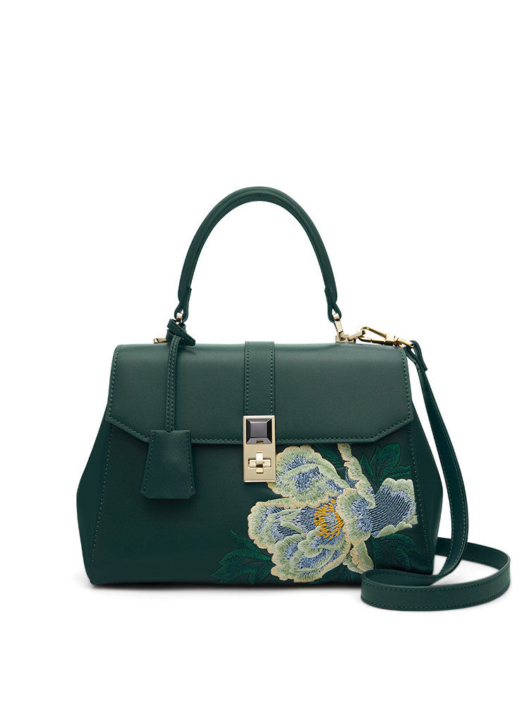 Green handbag with floral embroidery on a white background