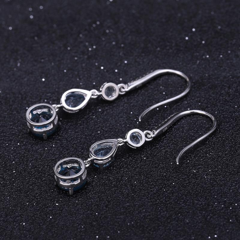 Silver earrings with gemstones on a dark textured background