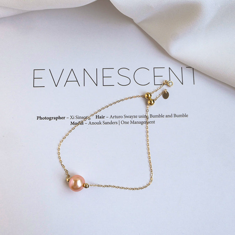 Gold bracelet with a pink pearl on a white background, featuring the brand 'Evanescent'.
