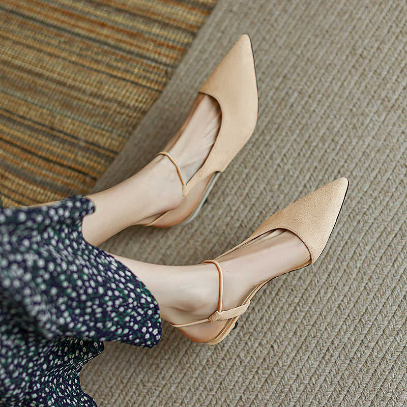 Beige pointed-toe shoes worn by a person on a textured surface